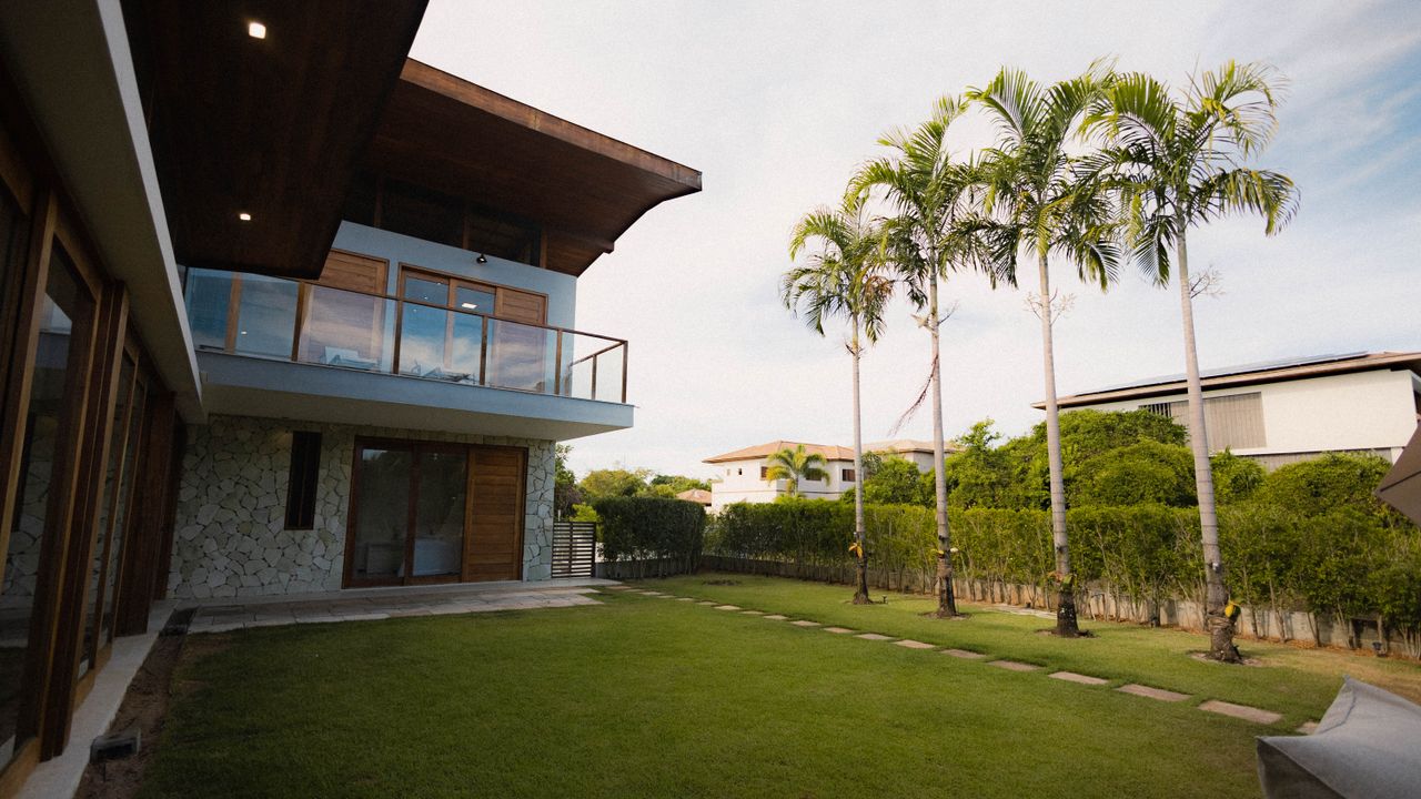 Contemporary home with palm trees, a lawn and a glass balcony